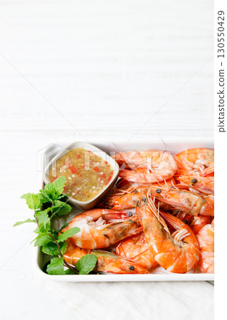 Grilled shrimps with spicy sauce in a white tray. 130550429