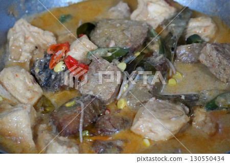 Authentic Ikan Pe, a traditional Indonesian dish from Surabaya, East Java. Smoked stingray curry with rice cake, tofu, and vegetables in rich coconut milk. 130550434