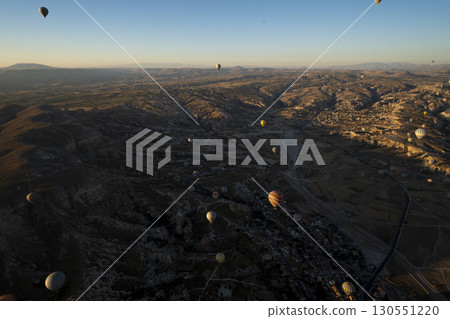 Türkiye Cappadocia: A landscape of strangely shaped mountains and many hot air balloons flying in the sky. 130551220