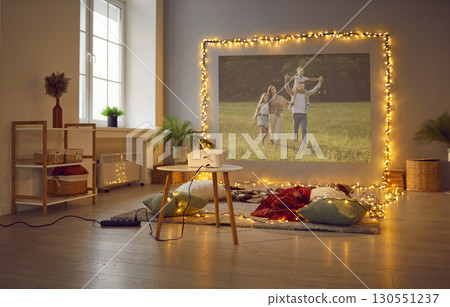 Living room interior with decorations, projector, family videos on wall, rug and pillows on floor 130551237