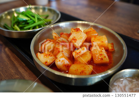 Traditional Korean Radish Kimchi and Fresh Green Onion Side Dish in Brass Bowl 130551477