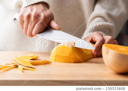 Woman hand holding kitchen knife and peeling butternut squash, Homemade cooking 130551608