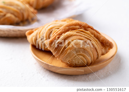 Curry puff stuffed with chicken or sweet potatoes on wooden plate with white background 130551617
