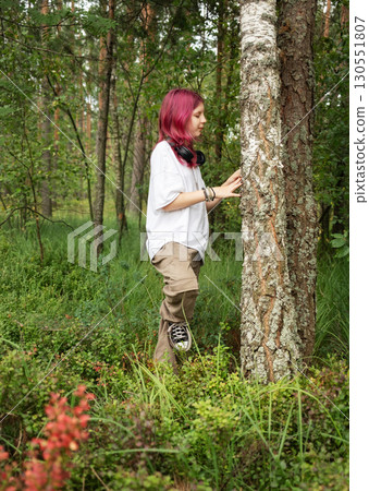 Young girl with pink hair exploring forest and touching tree trunk Young girl with pink hair exploring forest and touching tree trunk 130551807