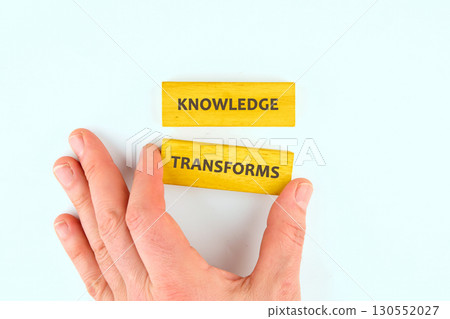 Knowledge learning innovation concept. KNOWLEDGE TRANSFORMS words made from blocks by hand on a light background, top view 130552027