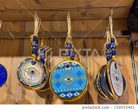 Traditional evil eye amulets with blue beads and golden details hanging in a shop. Protection, cultural belief, and spiritual heritage expressed through handcrafted talismans. 130553461