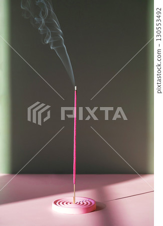 Pink incense stick burning with smoke trail. Aroma for relaxation and meditation. 130553492