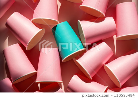 Teal paper cup stands out among many pink paper cups. Individuality, creativity, and uniqueness concept. 130553494