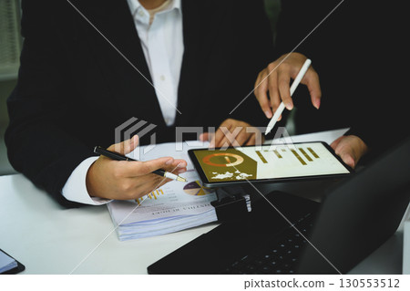 Businesspeople collaborating on project, reviewing charts and graphs on digital tablet 130553512