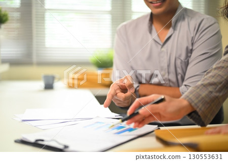 Close up of employees reviewing paperwork, collaboration and planning during discussion 130553631