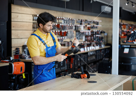 A man working on a grinding machine in a store A man working on a grinding machine in a store 130554092