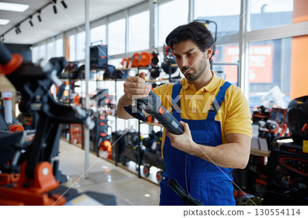 A man worker is holding a polisher in a store A man worker is holding a polisher in a store 130554114