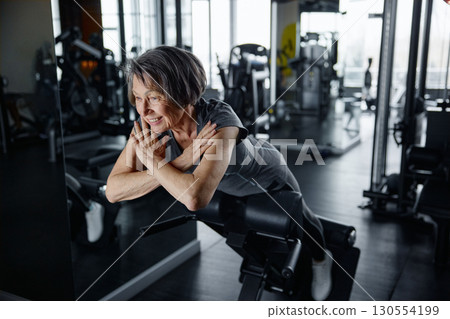 An elderly woman actively exercising in a modern gym facility 130554199