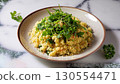 Couscous garnished with greens in a plate on a white marble serving table 130554471