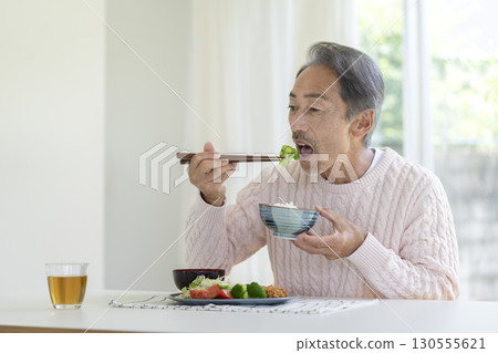 一名 60 多歲的男子正在吃飯 一名 60 多歲的男子正在吃飯 130555621