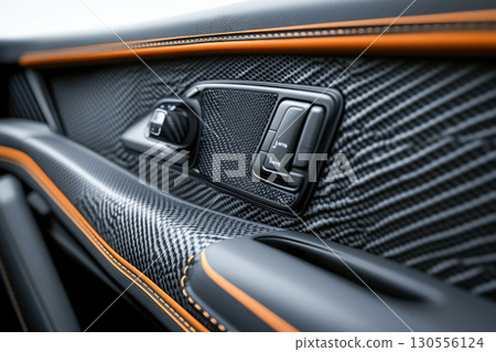 Close up of modern luxury car door panel showcasing carbon fiber texture and vibrant orange stitching. High tech automotive interior detail. Close up of modern luxury car door panel showcasing carbon fiber texture and vibrant orange stitching. High tech automotive interior detail. 130556124