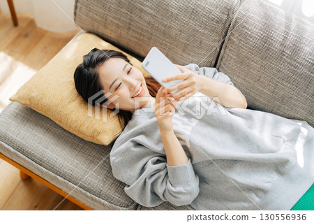 躺在沙發上使用智能手機的女人 130556936