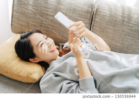 躺在沙發上使用智能手機的女人 130556944