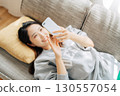 躺在沙發上使用智能手機的女人 130557054