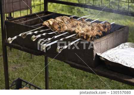 Juicy slices of meat prepare on the fire. Tasty shish kebab on skewers. Grilled marinated barbecue meat - shashlik on pork 130557080