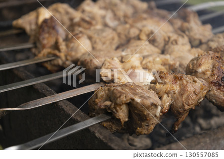 Juicy slices of meat prepare on the fire. Tasty shish kebab on skewers. Grilled marinated barbecue meat - shashlik on pork Juicy slices of meat prepare on the fire. Tasty shish kebab on skewers. Grilled marinated barbecue meat - shashlik on pork 130557085