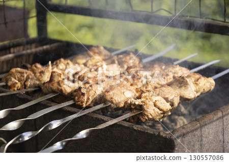 Juicy slices of meat prepare on the fire. Tasty shish kebab on skewers. Grilled marinated barbecue meat - shashlik on pork 130557086