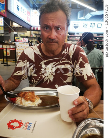 大阪世博會上，一名男子一邊吃咖哩豬排，一邊喝啤酒 130557219