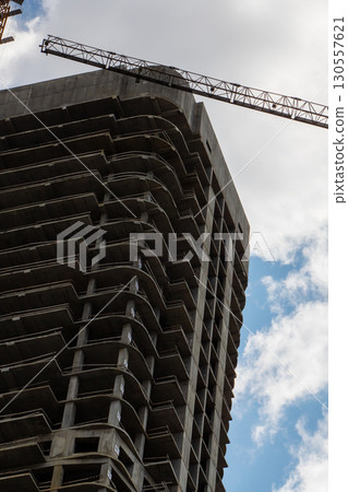 A large building under construction with a crane on top 130557621