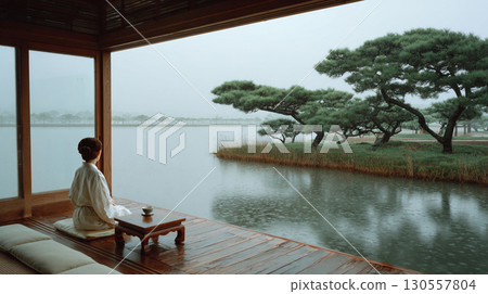Meditating by a rainy lake with a cup of tea in a tranquil Japanese garden 130557804