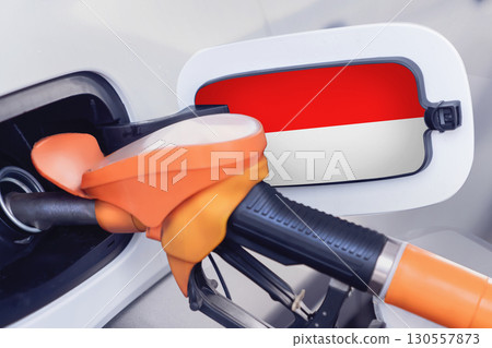 The flag of Indonesia on the lid of the gas tank of a car at a gas station in close-up. High or low gasoline prices at Indonesian gas stations. In Indonesia, gasoline prices are rising due to a The flag of Indonesia on the lid of the gas tank of a car at a gas station in close-up. High or low gasoline prices at Indonesian gas stations. In Indonesia, gasoline prices are rising due to a 130557873