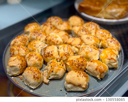 Plate of small baked rolls with golden crust and sesame seeds. Everyday nutrition, culinary tradition, and cultural lifestyle in simple handmade bread. Plate of small baked rolls with golden crust and sesame seeds. Everyday nutrition, culinary tradition, and cultural lifestyle in simple handmade bread. 130558085