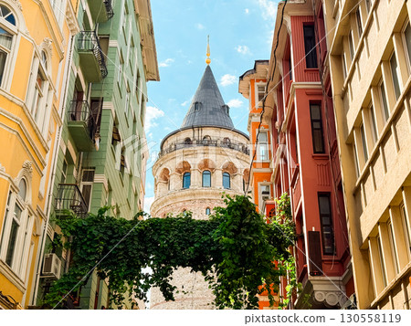 Galata Tower rising between colorful residential buildings in the historic district of Istanbul. Urban heritage, architectural identity, and cultural landmark in the city. 130558119