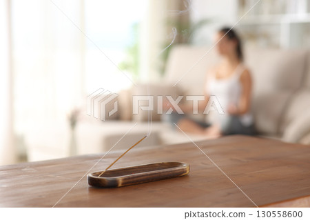 Incense stick burning with a woman doing yoga at home 130558600