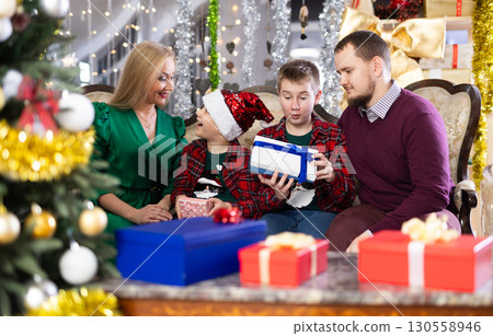 Children and parents give each other gift boxes during Christmas or New Year celebrations at home Children and parents give each other gift boxes during Christmas or New Year celebrations at home 130558946