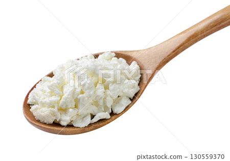 Cottage cheese in a wooden spoon close-up on a white. Isolated Cottage cheese in a wooden spoon close-up on a white. Isolated 130559370