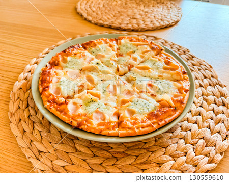 Fresh baked pizza served on plate with woven stand. Culinary enjoyment, leisure and gastronomy in everyday lifestyle. 130559610