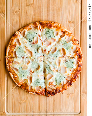 Sliced pizza with visible pieces and toppings on wooden board. Sharing, leisure and culinary enjoyment in everyday dining. 130559617