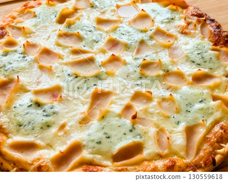 Whole baked pizza with cheese and toppings on wooden board close-up. Food, leisure and culinary lifestyle in homemade dining culture. Whole baked pizza with cheese and toppings on wooden board close-up. Food, leisure and culinary lifestyle in homemade dining culture. 130559618