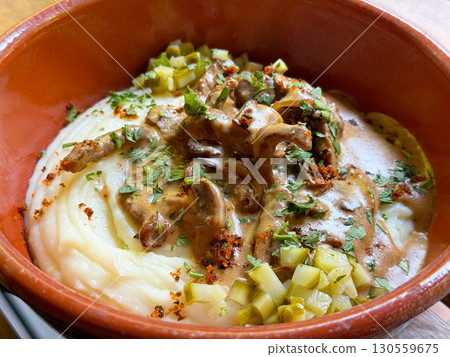 Traditional meat with mashed potatoes served in a clay bowl close-up. Comfort, taste, and cultural richness of homemade cuisine. 130559675