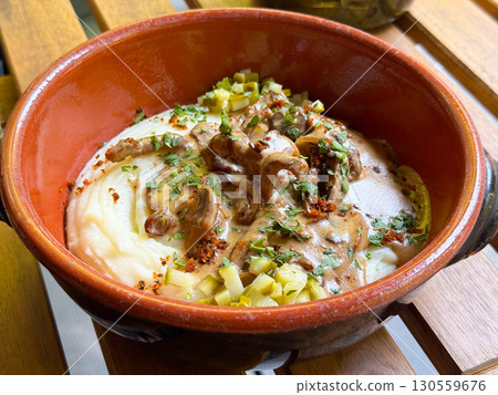 Traditional meat with mashed potatoes served in a clay bowl. Comfort, taste, and cultural richness of homemade cuisine. 130559676