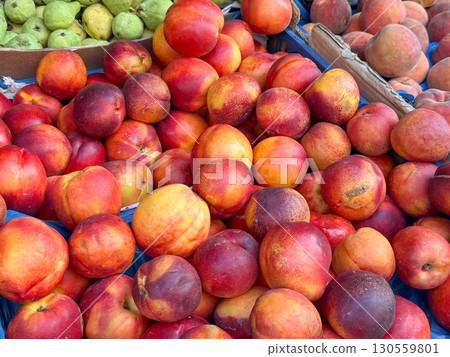 Fresh nectarines stacked at market stall. Harvest, nutrition, and seasonal fruit trade highlighting agriculture, orchard supply, and natural abundance for healthy lifestyle. 130559801