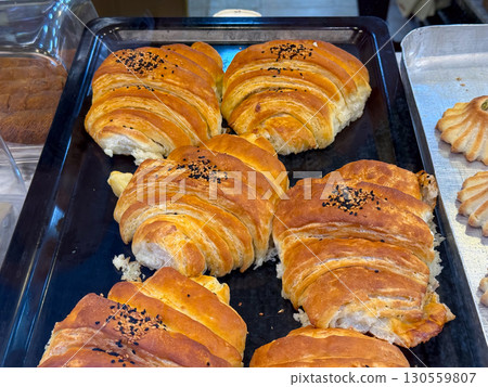 Fresh croissants with sesame seeds on bakery tray. Culinary tradition, breakfast food, and indulgence combining cultural recipe, artisan preparation, and golden pastry enjoyment. Fresh croissants with sesame seeds on bakery tray. Culinary tradition, breakfast food, and indulgence combining cultural recipe, artisan preparation, and golden pastry enjoyment. 130559807