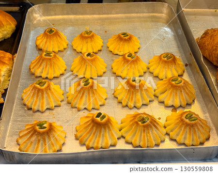 Pastry cookies with pistachio decoration on tray. Tradition, culture, dessert preparation, and sweet indulgence representing bakery product, gourmet taste, and culinary lifestyle. Pastry cookies with pistachio decoration on tray. Tradition, culture, dessert preparation, and sweet indulgence representing bakery product, gourmet taste, and culinary lifestyle. 130559808