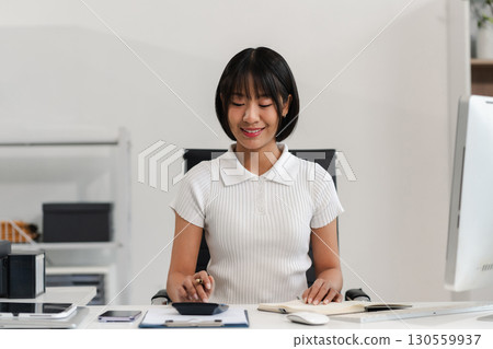 Female businessman hand using calculator and writing make note with calculate about cost at home office. Female businessman hand using calculator and writing make note with calculate about cost at home office. 130559937