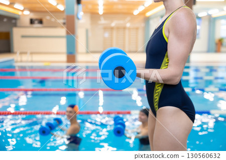 Group of women having aqua fitness class and exercising with dumbbells Group of women having aqua fitness class and exercising with dumbbells 130560632