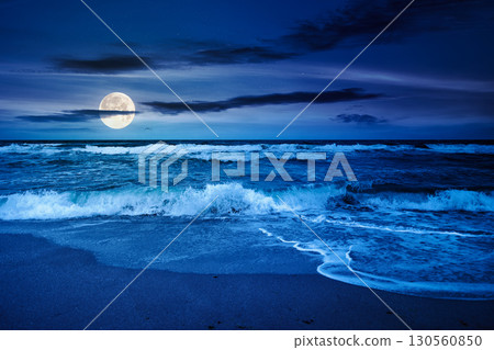 stormy beach scenery with waves splash on sand shore under scenic clouds on the sky at night. dark moody nature background for travel. scenic view of european coast in full moon light stormy beach scenery with waves splash on sand shore under scenic clouds on the sky at night. dark moody nature background for travel. scenic view of european coast in full moon light 130560850