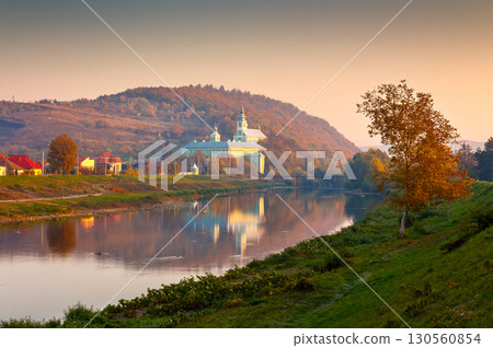 mukachevo, ukraine - 06 nov, 2015: urban landscape with river and trees in autumn. reflection of a monastery in the distance. beautiful travel destination of transcarpathia 130560854