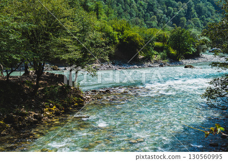 Free blue mountain rock river among forested mountains on sunny day 130560995