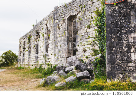 Ancient stone dilapidated fortress with window openings, entrance and pile of stones Ancient stone dilapidated fortress with window openings, entrance and pile of stones 130561003