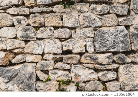 Gray stone wall made of old cobblestones, part of the fortress 130561004